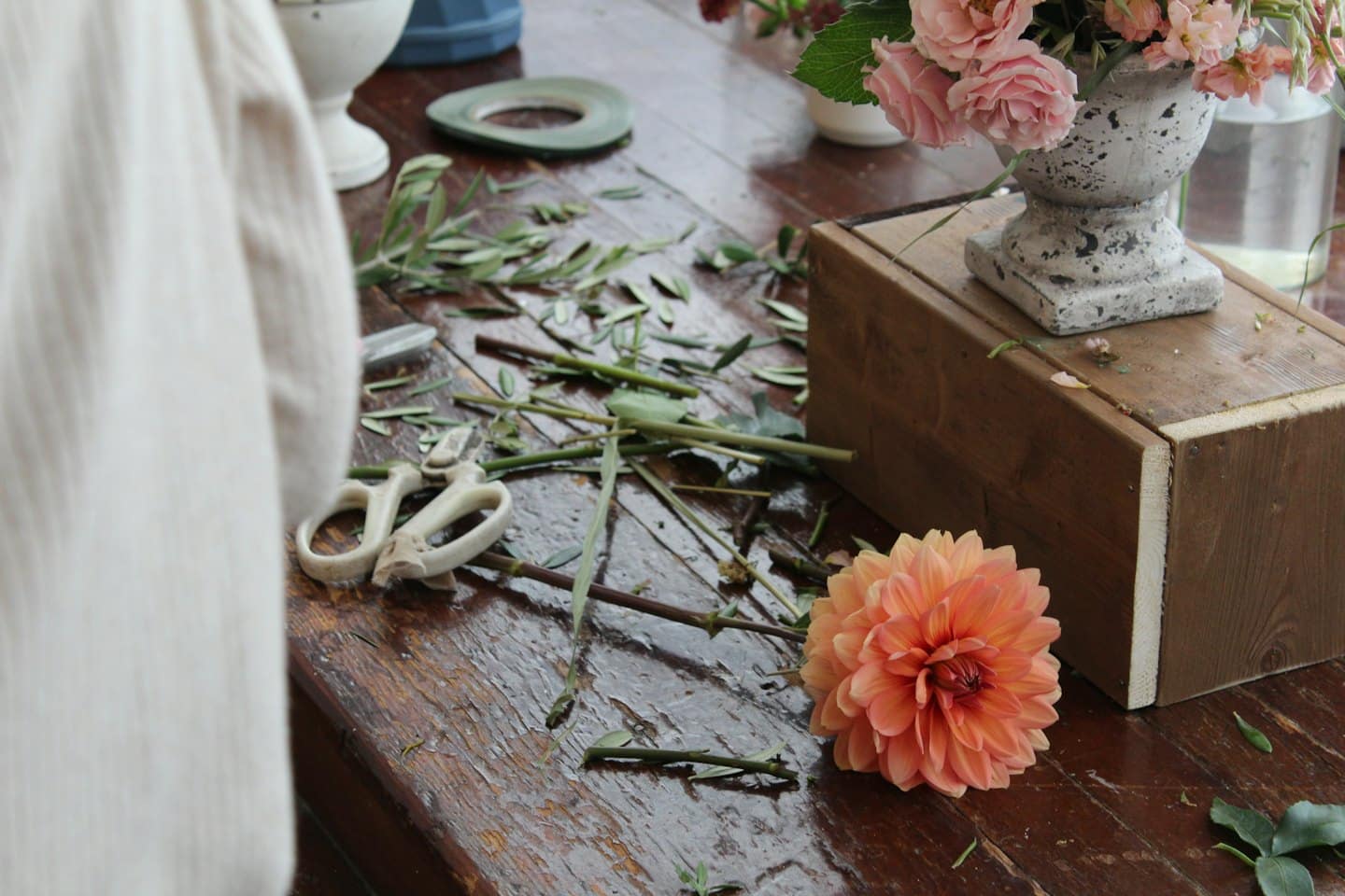 Rustieke tafel van een bloemist met dahlia's, rozen en een snoeischaar.