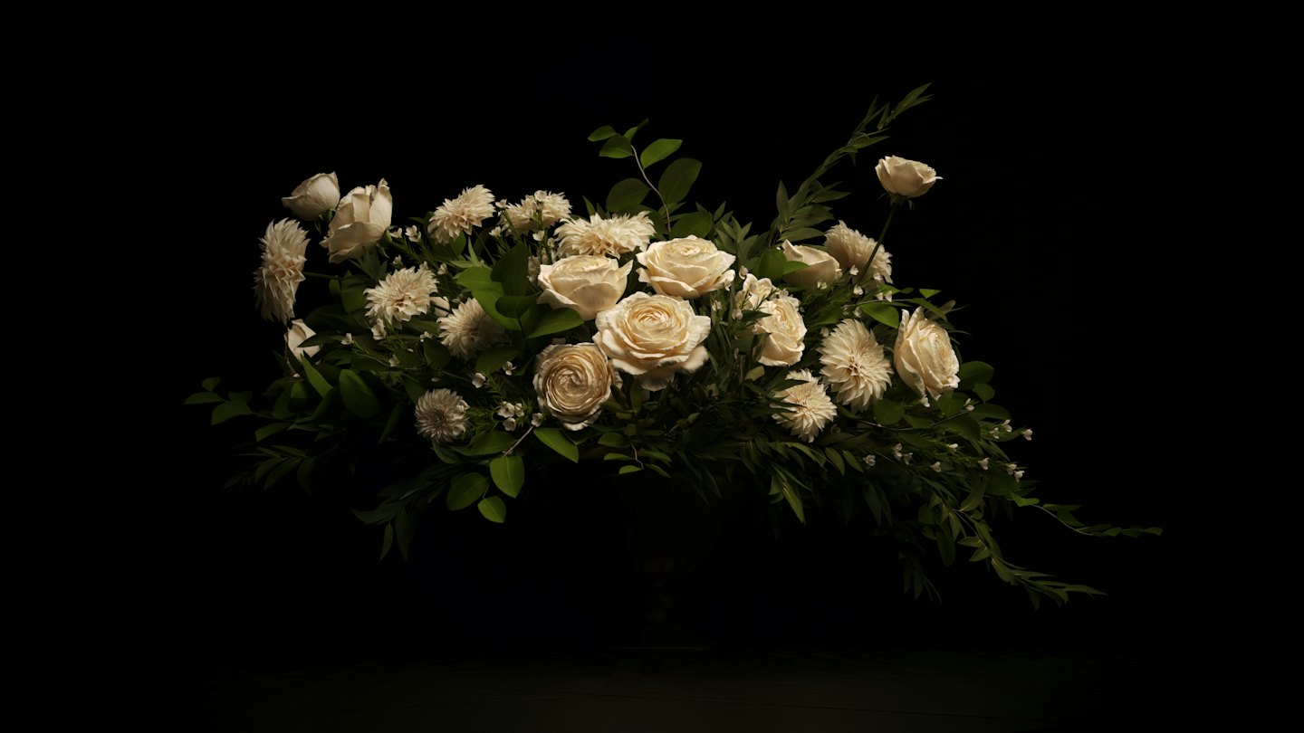 Crèmekleurige rozen en witte chrysanten in een bloemstuk.